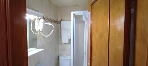 uma casa de banho com um WC, um lavatório e um espelho. em Hospedaje Bar El Gato del Acueducto na Segóvia