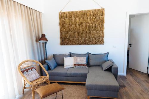 a living room with a blue couch and a chair at Monte da Fonte in Zambujeira do Mar