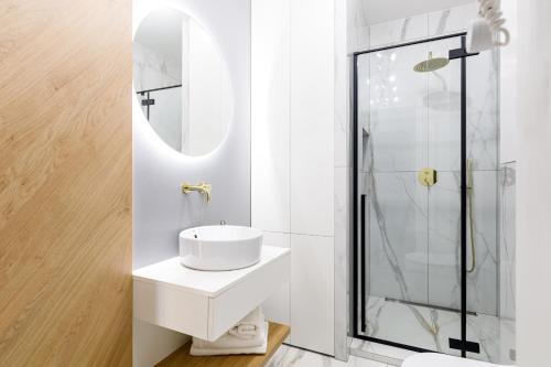 a white bathroom with a sink and a shower at Balticus Apartamenty Deluxe Promenada Gwiazd 14 in Międzyzdroje