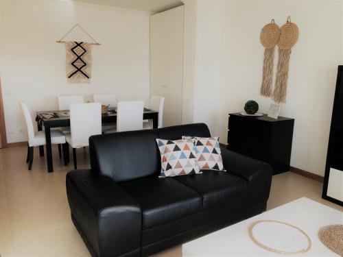 a black leather couch in a living room with a table at Apartamento Mar com Parking in Nazaré