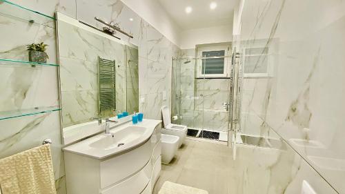 a white bathroom with a sink and a shower at Appartamento Casa Crispino Piano terra per 2 persone in Frattaminore
