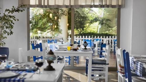 a dining room with white tables and blue chairs at TUI BLUE Tropical in Dalaman