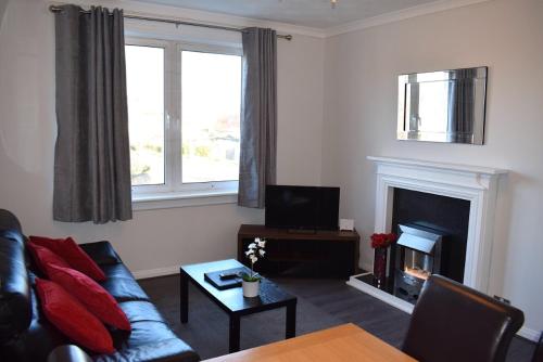 een woonkamer met een bank en een open haard bij Kelpies Serviced Apartments - McClean in Falkirk