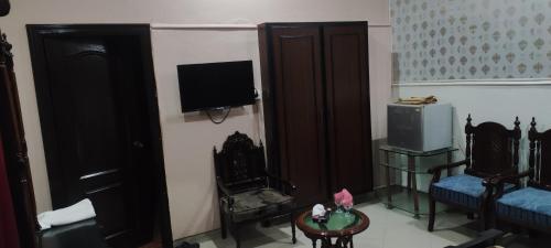 a living room with a tv and two chairs and a table at Hotel Shelton Palace in Multan