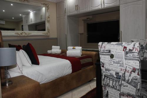 um quarto com uma cama grande e uma televisão em Romans Rest Guest House em Carletonville