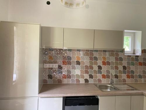 a kitchen with a sink and a tiled wall at Rózsa Vendégház Balatonfüred in Balatonfüred