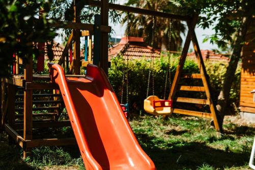 un parque infantil con un tobogán y un columpio de madera en Naz Beach Bungalow Hotel in Antalya, en Kızılot