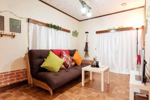 a living room with a brown couch with colorful pillows at Forest Villa Hakone in Hakone