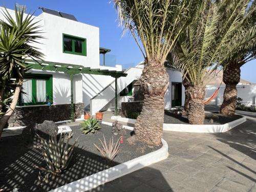 une maison blanche avec des palmiers devant elle dans l'établissement Vivienda Vacacional Casa del Erizo - Ecofinca, à Nazaret