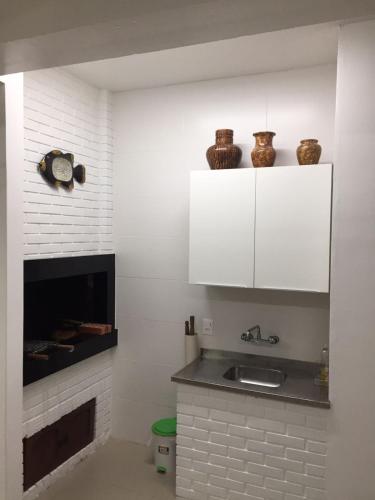 a kitchen with a sink and a fireplace at Casa beira mar Torres in Torres
