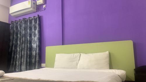 a bedroom with purple walls and a bed with a green headboard at Homewood Suites ( Service Apartments) in Hyderabad
