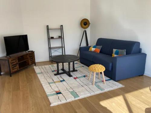 un salon avec un canapé bleu et une table dans l'établissement Centre-ville au calme grand T2 avec terrasse, à La Rochelle