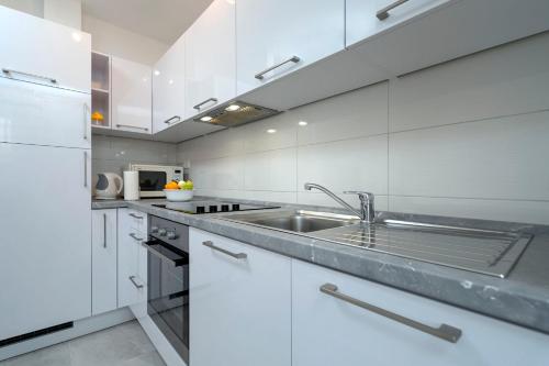 a kitchen with white cabinets and a stainless steel sink at Apartments Ena in Vrboska