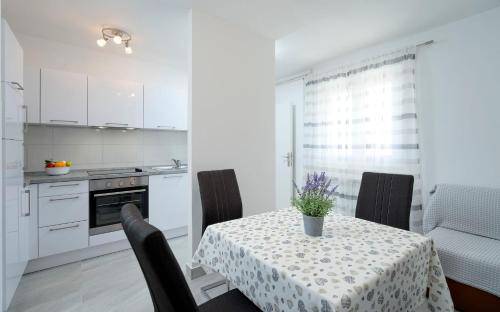a white kitchen with a table with chairs and a table cloth at Apartments Ena in Vrboska