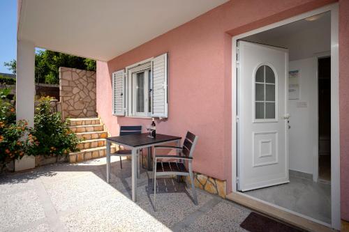 a table and chairs in front of a pink house at Apartments Ena in Vrboska