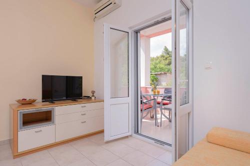 a living room with a tv and a sliding glass door at Apartments Ena in Vrboska