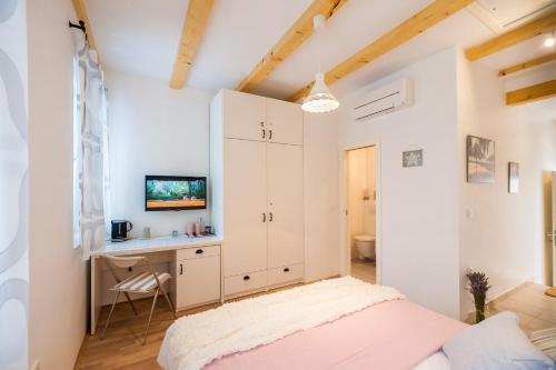 a white bedroom with a bed and a desk at Aldo Apartments Center in Zadar