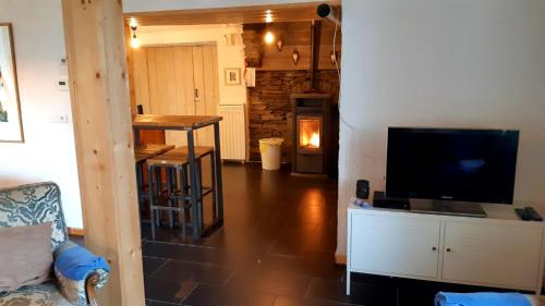 a living room with a television and a table with a fireplace at Maison-indi in Houffalize