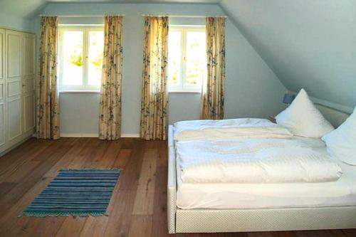 a bedroom with a bed and two windows and a rug at Holiday Home Witsum - DNS10055-F in Hedehusum