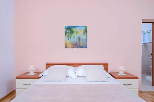 a bedroom with a bed with two nightstands and two lamps at Apartments Ena in Vrboska