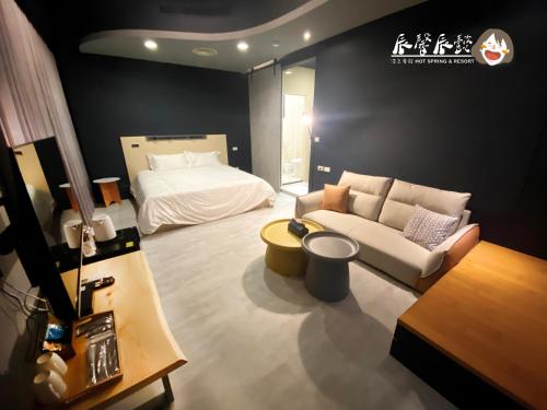 a living room with a bed and a couch at 辰馨辰懿溫泉會館 in Jiaoxi