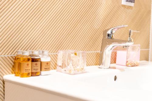 a bathroom sink with jars of honey and a faucet at AL-DOM apartamenty Apartament Stjarne in Kołobrzeg