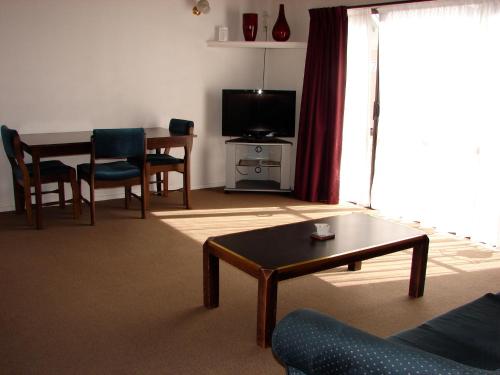 a living room with a couch and a table and a television at 193 Aorangi Manor Motel in Blenheim