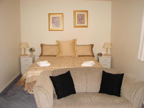 a bedroom with a bed with a couch and two lamps at 193 Aorangi Manor Motel in Blenheim