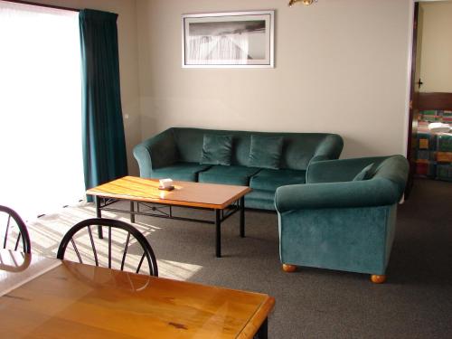 a living room with a couch and a table at 193 Aorangi Manor Motel in Blenheim