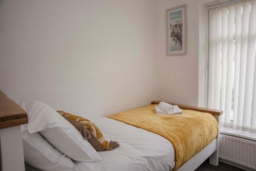 a bedroom with a bed with a yellow blanket and a window at Six Bells Retreat in Abertillery