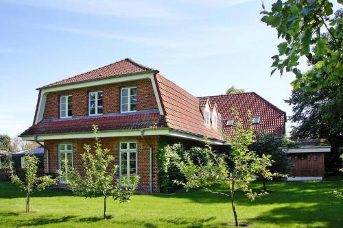 a red brick house with trees in front of it at Ferienwohnung im Gutshaus Schulenbrook in Metelsdorf