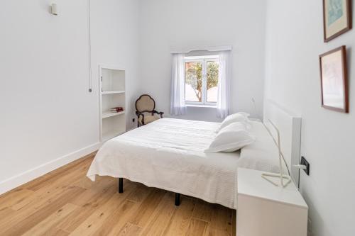 a white bedroom with a bed and a window at Albor Suites in Santa Brígida