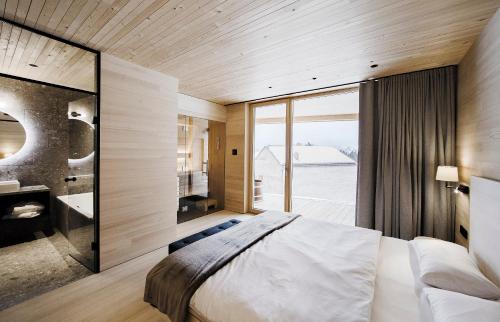 a bedroom with a large bed and a large window at Peterhof Chalets in Batschuns