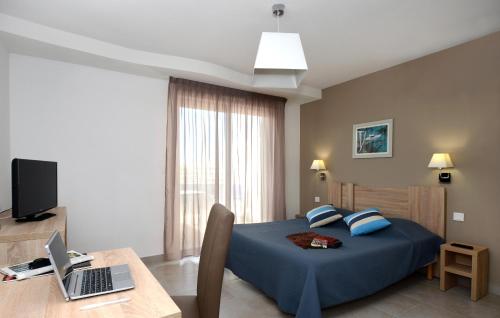 ル・バルカレスにあるRésidence Odalys Le Lotus Blancのベッドルーム1室(ベッド1台、ノートパソコン付きのデスク付)