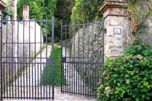 an iron gate with a stone wall and plants at Rustic House in Tuscany with Shared Pool in Ripafratta