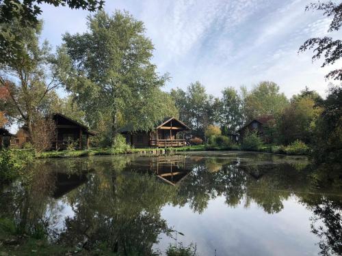 a view of a lake with two cottages at Ferienpark Geesthof in Hechthausen