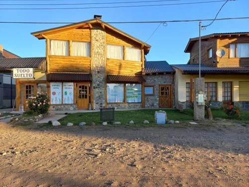 a large wooden house with a sign in front of it at LA CASA DE COCO ALOJAMIENTO TURÍSTICO in Dina Huapi
