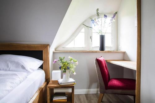 een slaapkamer met een bed, een rode stoel en een raam bij Holiday house, Fuhlendorf in Fuhlendorf