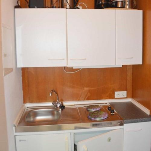 a kitchen with a sink and white cabinets at Apartmenthaus Spreewaldperle in Burg