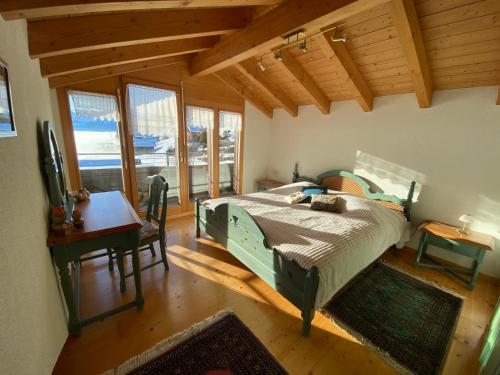 um quarto com uma cama, uma secretária e janelas em Alpenparadies em Beatenberg