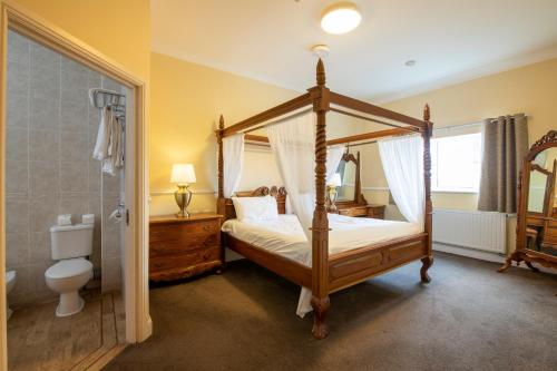 a bedroom with a four poster bed and a shower at Southview Park Hotel in Skegness