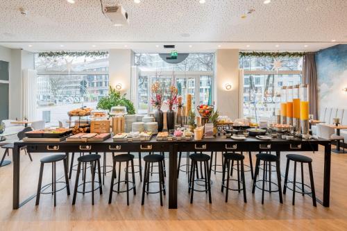 a large table with bar stools in a room at KOOS Hotel&Apartments - City Aparthotel in Munich