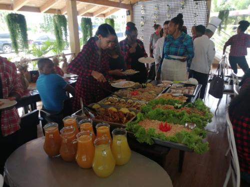 un grupo de personas de pie alrededor de un buffet de comida en My Home Hotel Punta Cana en Punta Cana