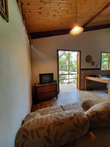a bedroom with a large bed and a tv in it at Chalé Filhos da Terra in São Francisco Xavier