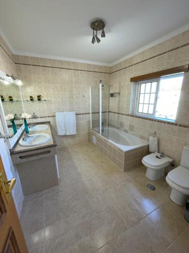 a bathroom with a tub and a sink and a toilet at Villa 3 Irmãos in Alvor