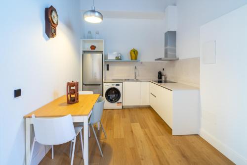 a kitchen with a wooden table and white cabinets at Albor Suites in Santa Brígida