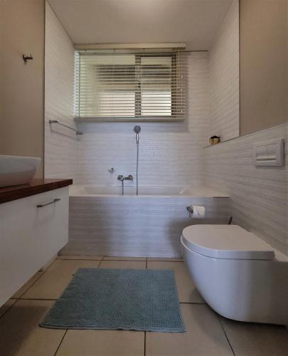a bathroom with a tub and a toilet and a sink at On The Beach At Strand in Strand