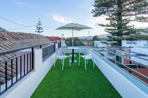 a balcony with a table and chairs and an umbrella at Albor Suites in Santa Brígida