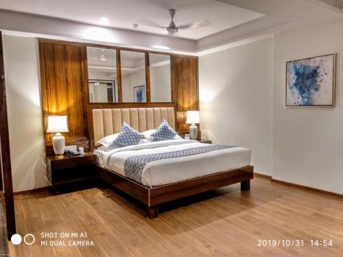 a bedroom with a bed and two lamps and a mirror at OAKTREE HOTEL in Morbi