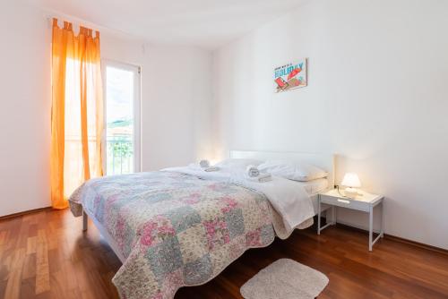 a white bedroom with a bed and a window at Apartment Lovorka 5 in Baška